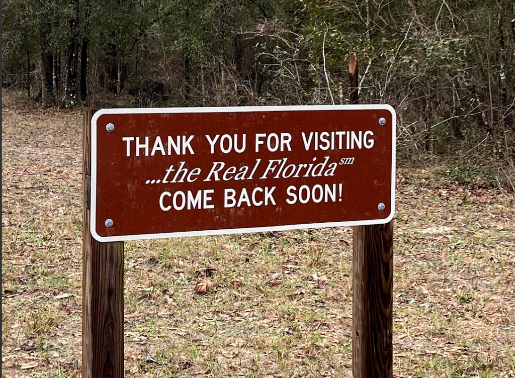 A sign in a wooded passage reads "Thank you for visiting... the Real Florida. Come back soon!"